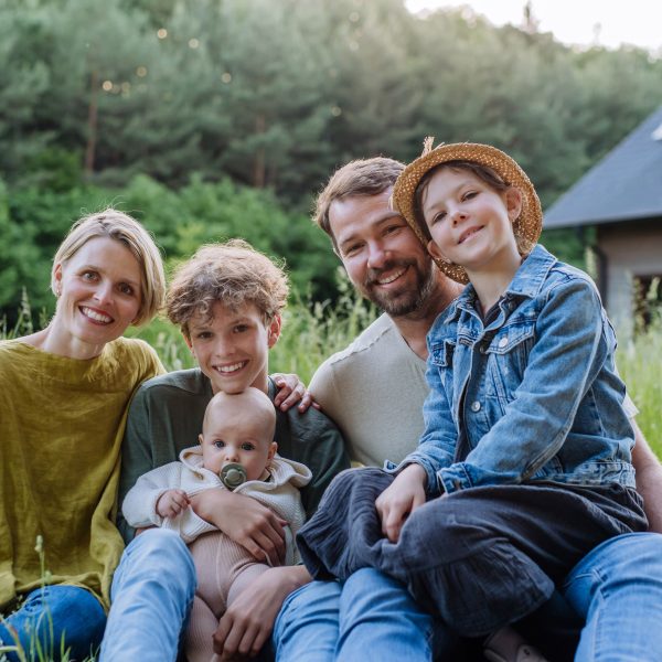 Junge Familie sitzt im Grünen vor ihrem Haus