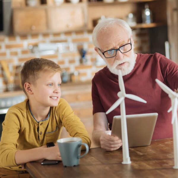 Opa erklärt seinem Enkel Windräder an kleine Modellen
